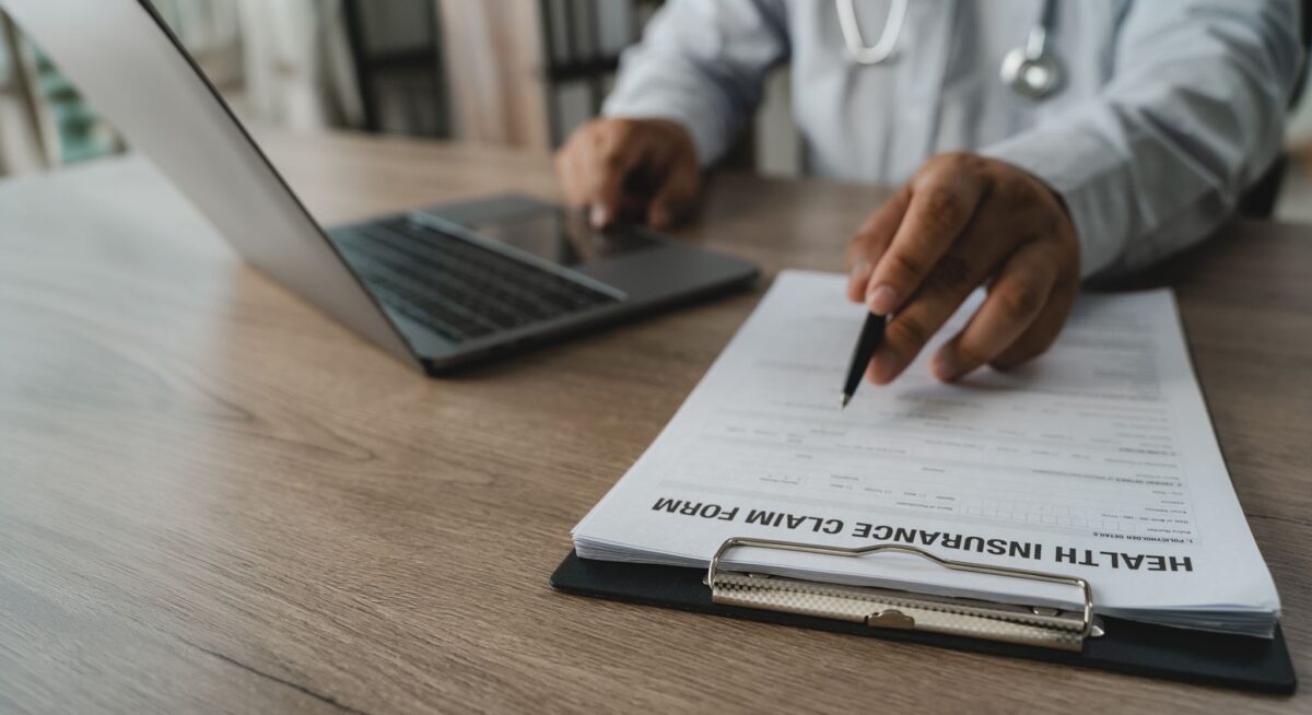 Close up of a hand holding a pen, carefully reviewing and analyzing a complex health insurance claim form and medical bill