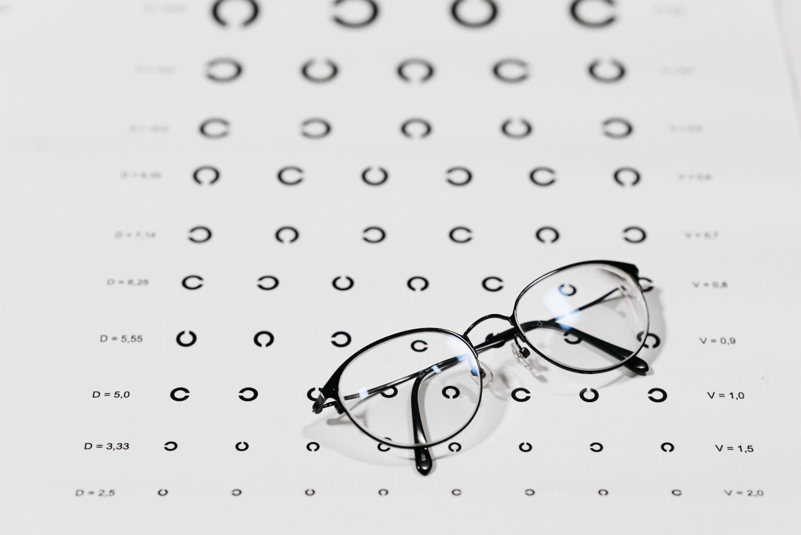 A pair of eyeglasses resting on an optician's measuring scale