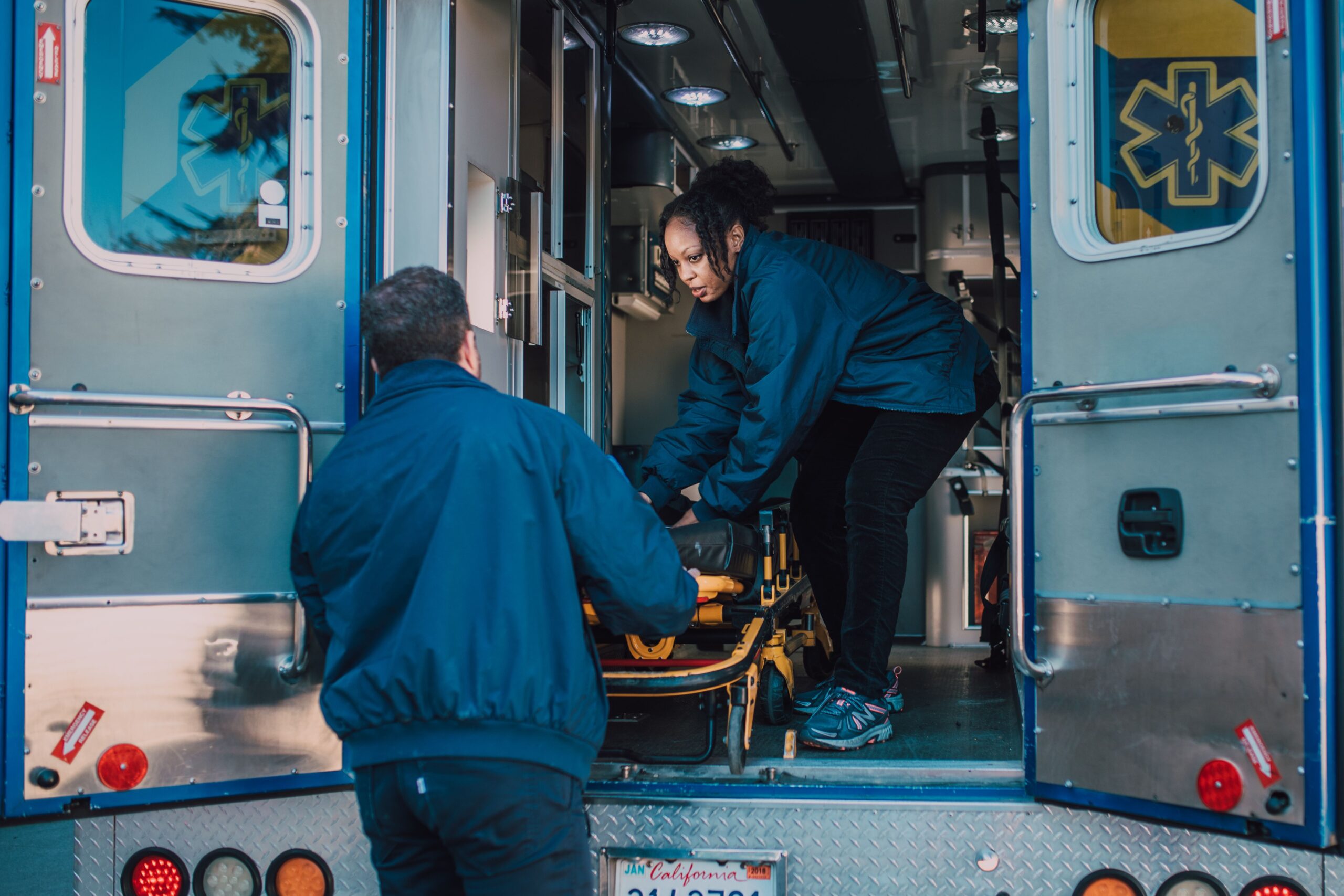 A paramedic pulling a stretcher out of an ambulance