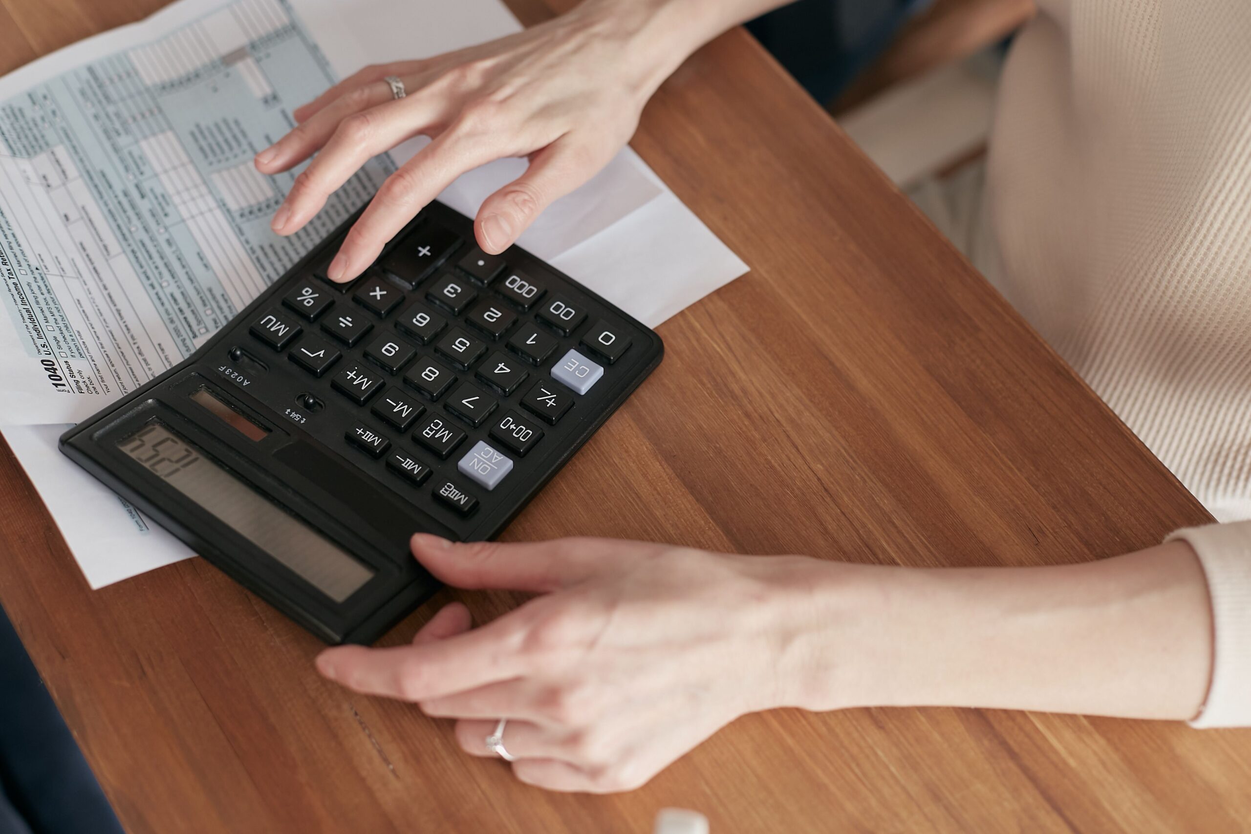 A woman working through her bills with a calculator at a home desk